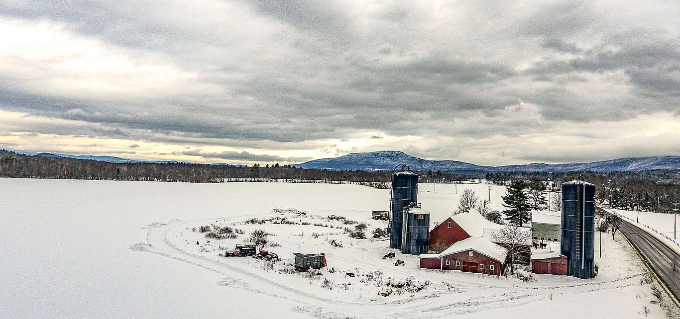 A snow-covered barn with three silos