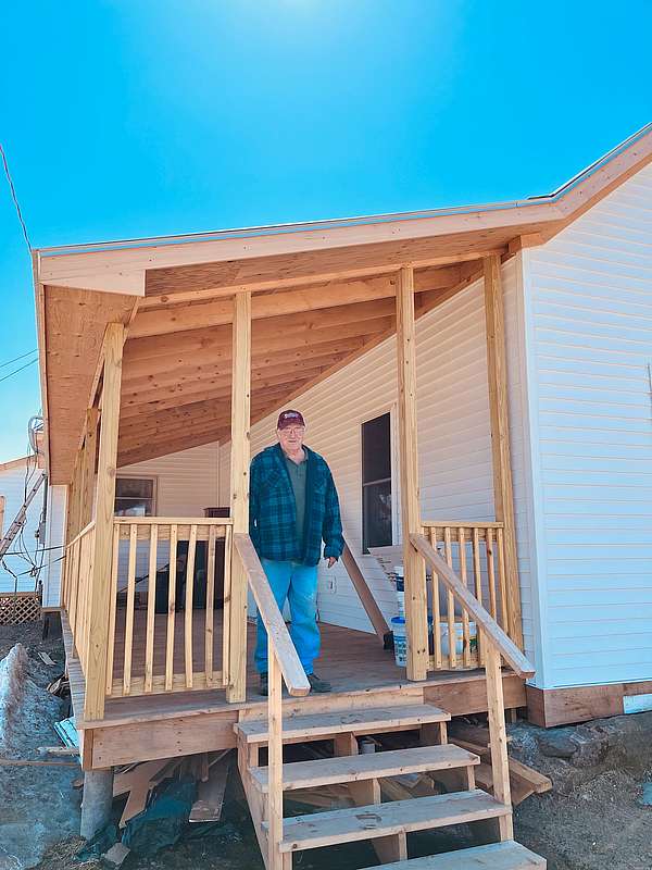 Paul Percy stands on a new porch built on farmworker housing.