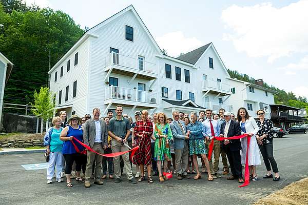 A group of community partners at a ribbon cutting to unveil a new housing project.